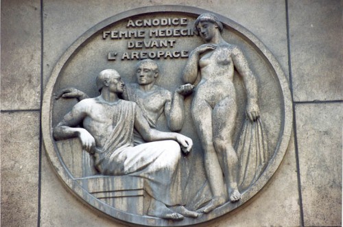 En el medallón se ve el momento en el que Agnodice se levanta sus ropas para enseñar al tribunal que era una mujer