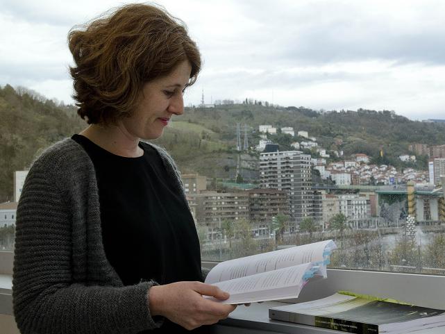 Maider Uriarte repasando su tesis con las laderas de los montes de Bilbao al fondo.
